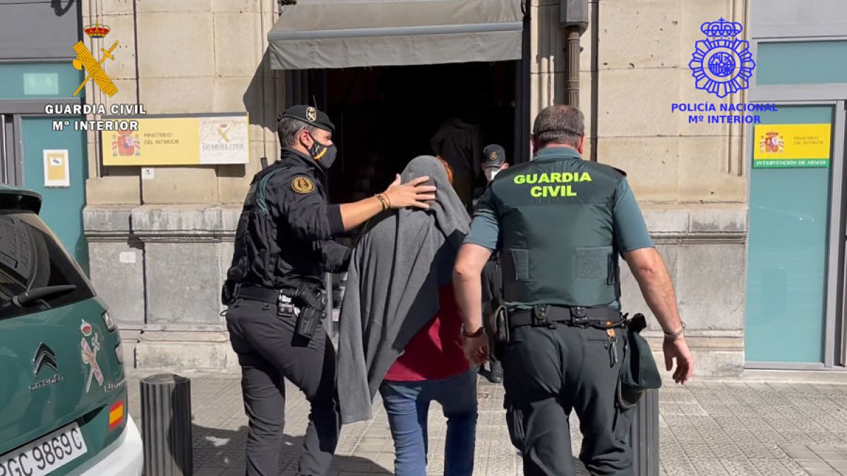 Dos agentes conducen a uno de los detenidos. ECB