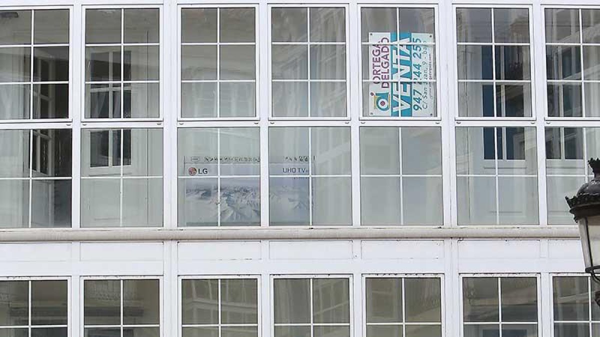 Dos personas pasan debajo de varios anuncios de venta de viviendas.