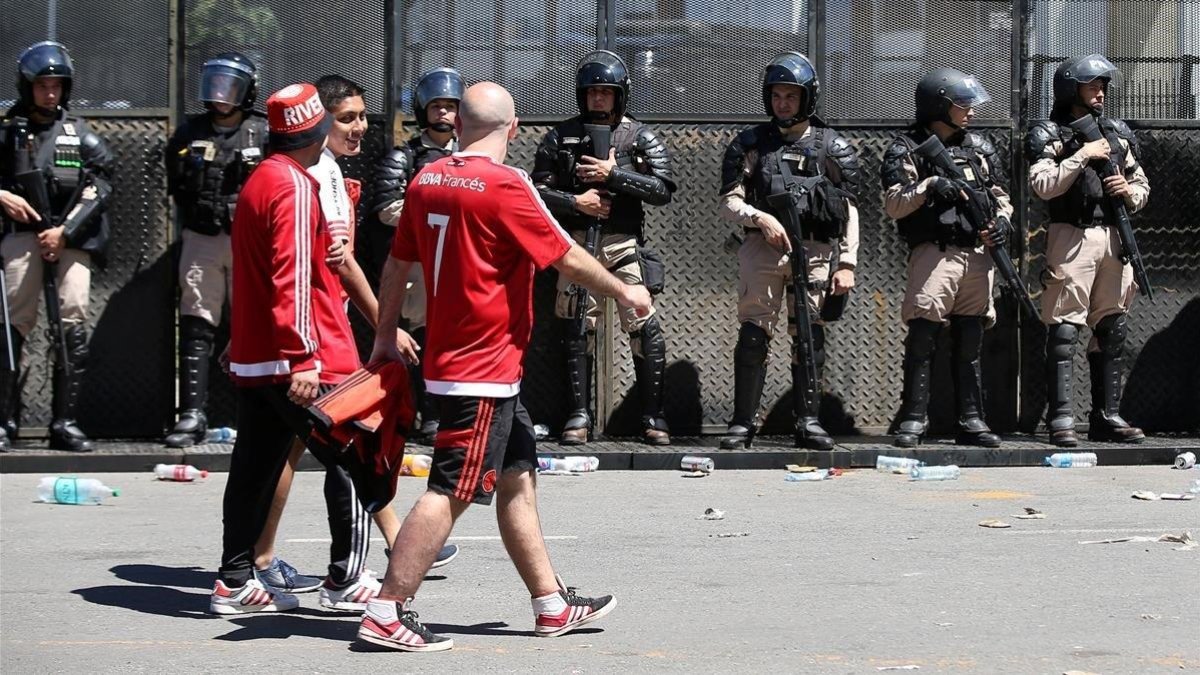 Aficionados del River pasan por delante de las fuerzas policiales tras la suspensión del partido el pasado sábado.-AGUSTÍN MACARIAN