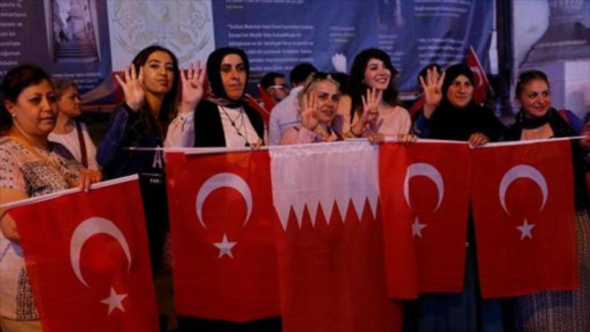 Mujeres con banderas turcas y qatarís en Estambul.-REUTERS / MURAD SEZER