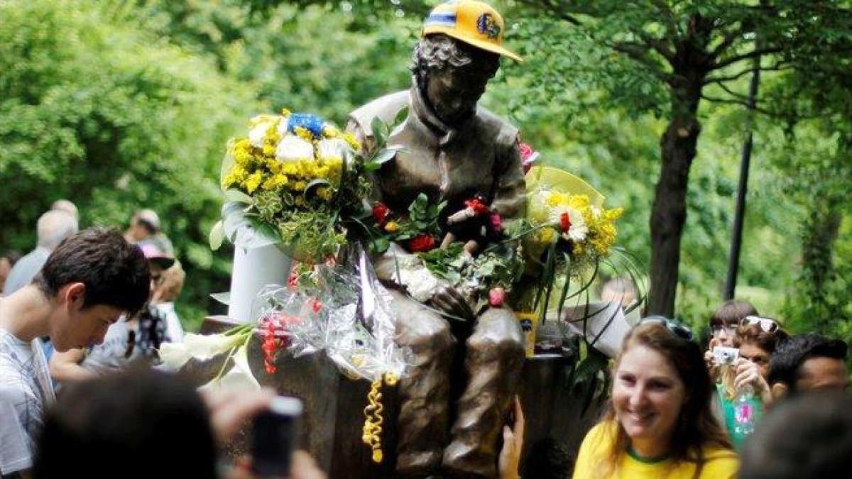 Una aficionada brasileña posa junto a la estatua que recuerda a Ayrton Senna en Imola.-REUTERS / ALESSANDRO GAROFALO