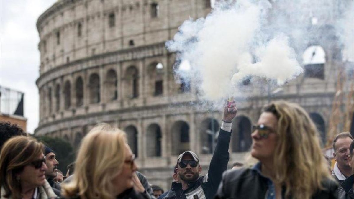 Un hombre alza una lata de humo durante una protesta frente al Coliseo de Roma Italia durante una huelga convocada hoy 23 de marzo de 2017 tras la reunion de ayer entre taxistas y gobierno en la que no se llego a un acuerdo-EFE / ANGELO CARCONI