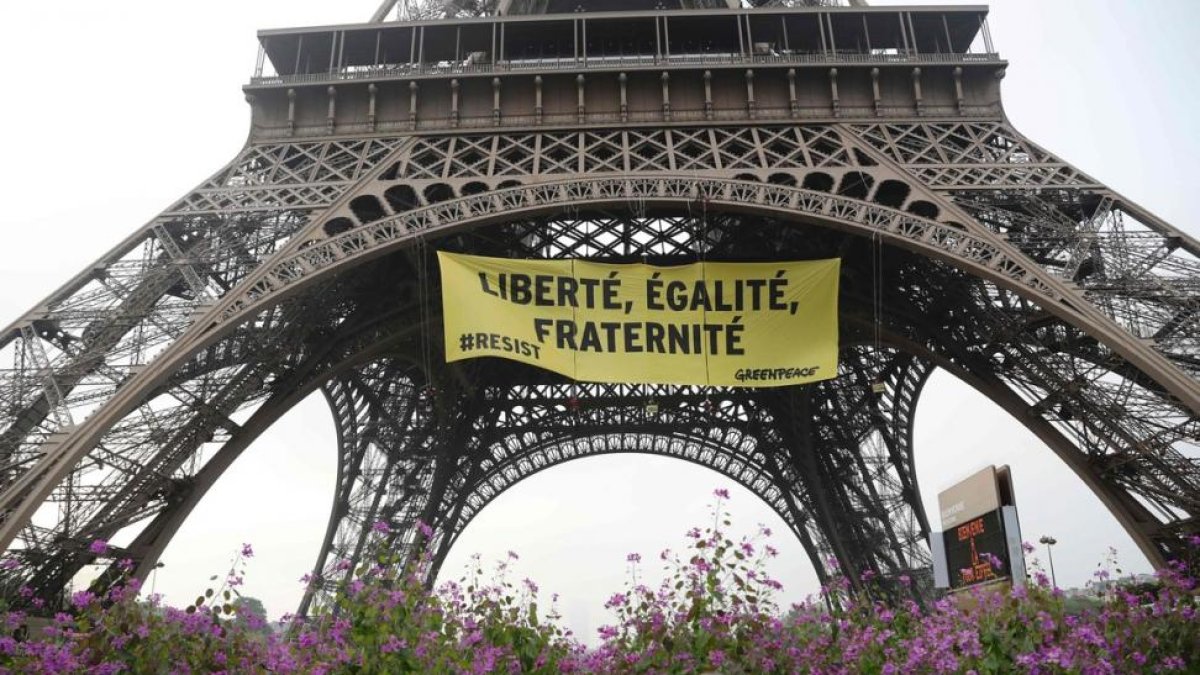 'Libertad, igualdad, fraternidad', se lee en la pancarta que Greenpeace ha colgado en la Torre Eiffel.-AFP