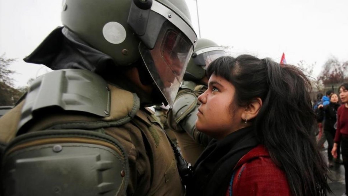 Una manifestante mira a un policía durante una marcha con motivo del 43 aniversario del golpe de Estado en Chile.-CARLOS VERA / REUTERS