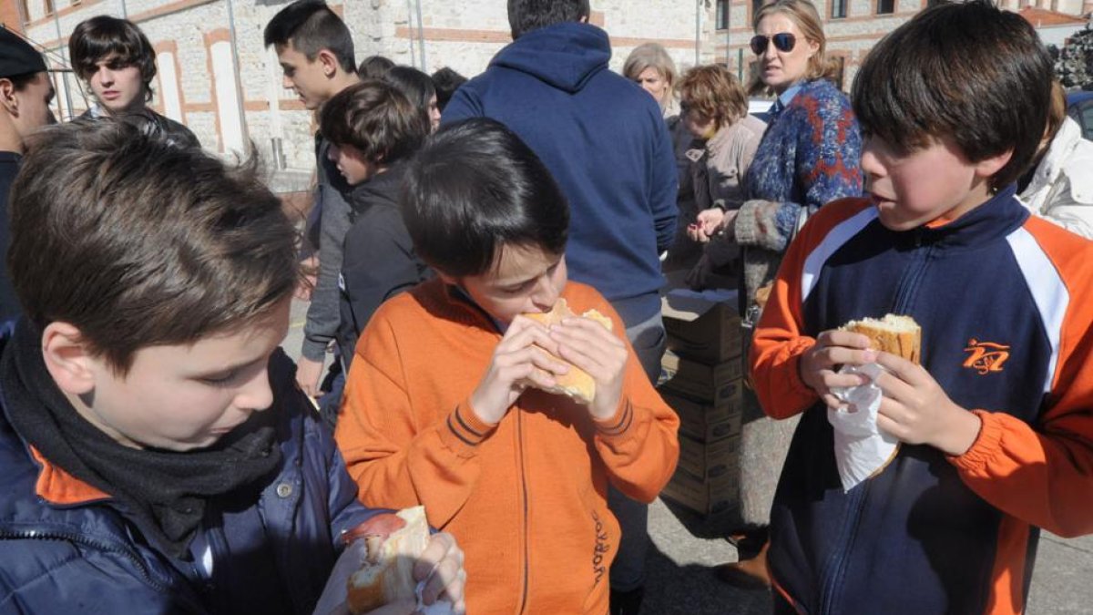 Tres niños comen con apetito la merienda más solidaria del año.-ISRAEL L. MURILLO