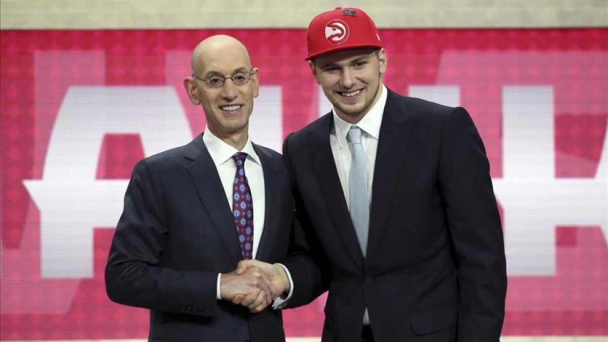 Luka Doncic saluda en el estrado a Adam Silver, comisionado de la NBA, tras su elección.-AP