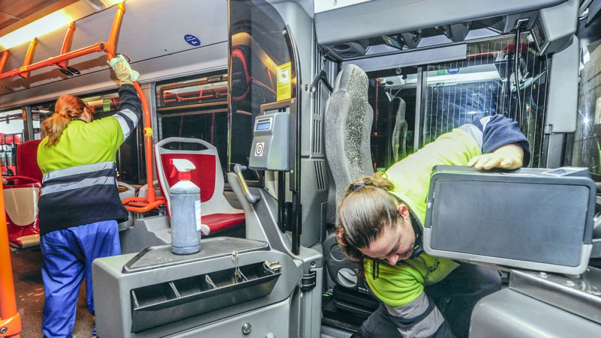 Dos trabajadoras limpian y desinfectan un autobús municipal para ponerlo a punto para los usuarios. ISRAEL L. MURILLO