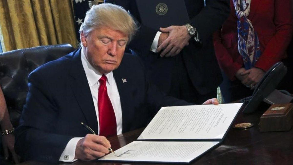 Donald Trump firma una orden ejecutiva en el Despacho Oval, este viernes.-