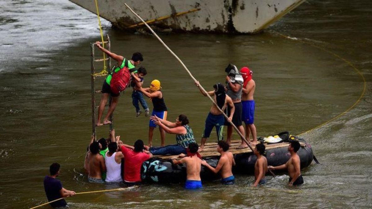 Inmigrantes hondureños socorren a un hombre y un niño en el río Suchiate, en el puente fronterizo de Ciudad Hidalgo, entre Guatemala y México, el 20 de octubre del 2018.-AFP / PEDRO PARDO
