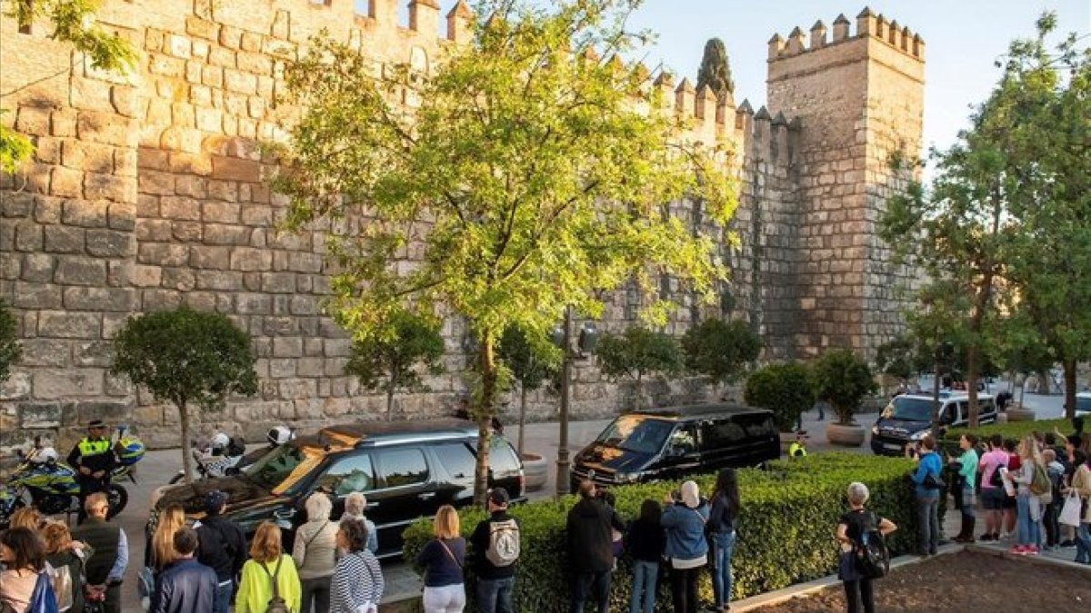 Un grupo de personas ve desfilar a la comitiva de Obama al llegar a los Alcázares.-EL PERIÓDICO