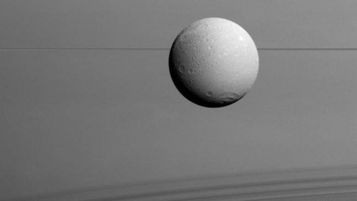 Panorámica de Dione con los anillos de Saturno al fondo.-Foto: NASA / ESA