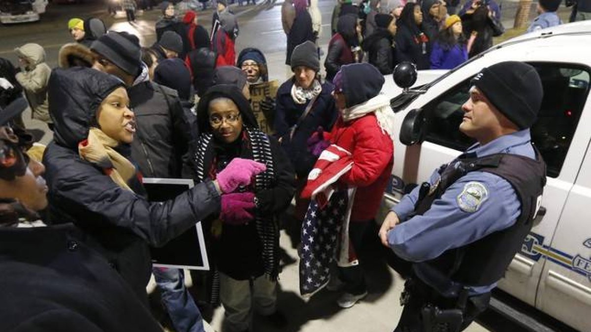 Una manifestante se encara con un policía, ante la comisaría de Ferguson, anoche, tras conocerse la decisión del Departamento de Justicia.-Foto: AP / CHARLES REX ARBOGAST