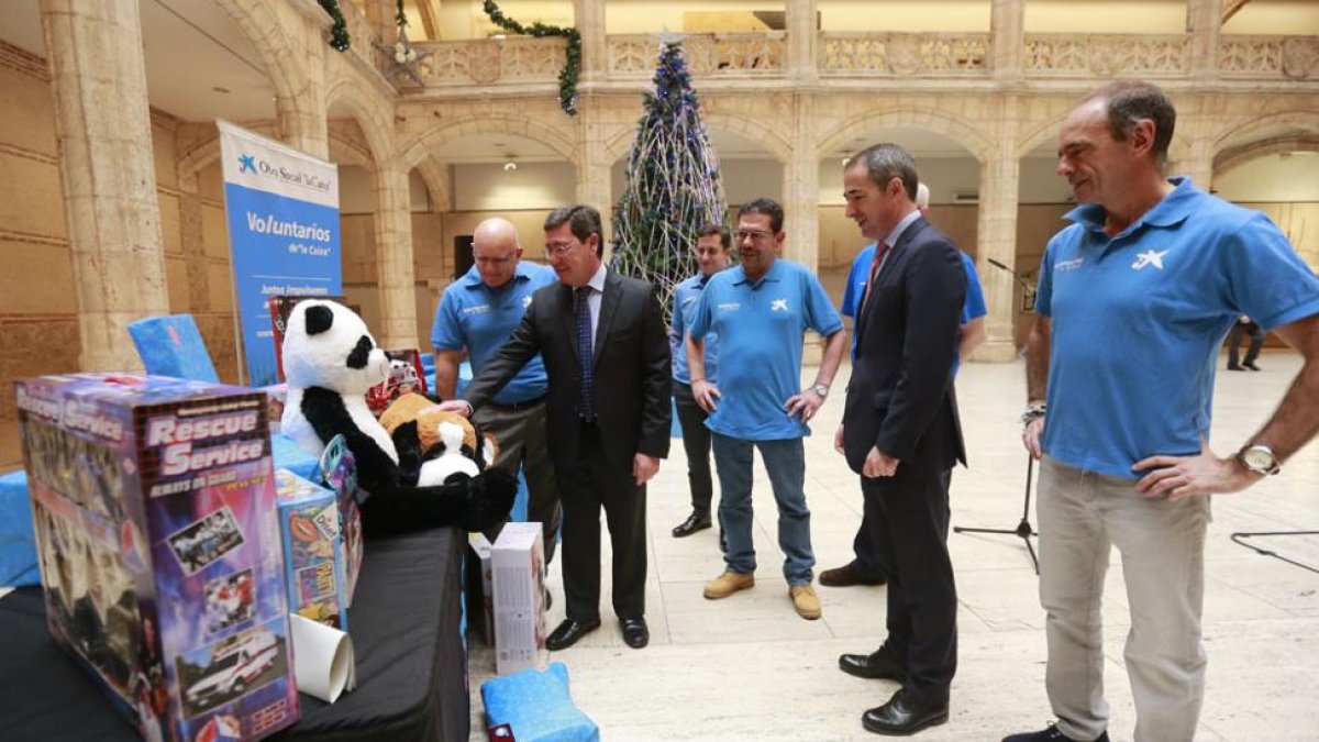 César Rico y Manuel Bilbao observan junto con klos voluntarios de ‘la Caixa’ los regalos que los niños recibirán estas navidades.-RAÚL OCHOA