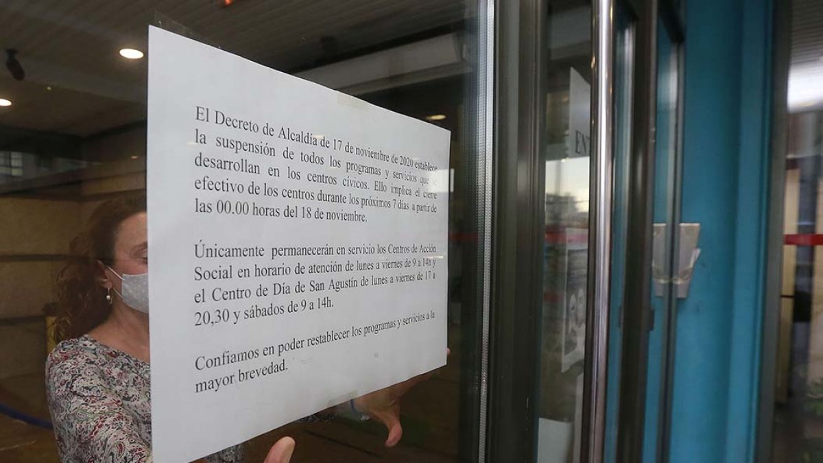 Una empleada del centro cívico de Río Vena coloca el aviso de que se suspenden las actividades por decreto del alcalde. RAÚL OCHOA
