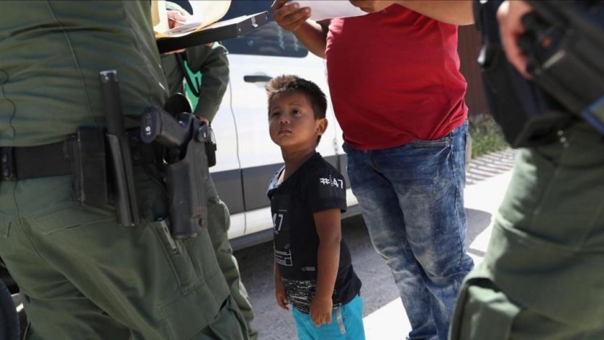 Un niño y sus padres, procedentes de Honduras, son retenidos por una patrulla policial cerca de la frontera de EEUU con México en Misión (Tejas), el 12 de junio pasado.-JOHN MOORE