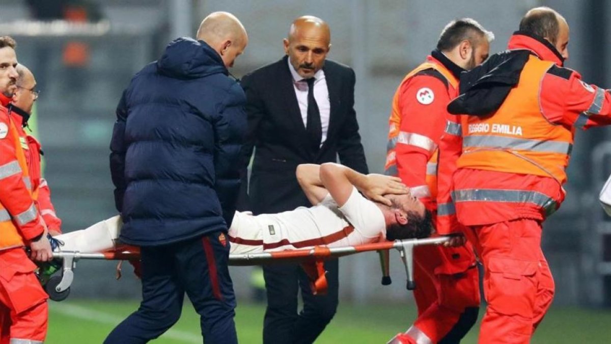 Los camilleros retiran a Alessandro Florenzi mientras su entrenador, Luciano Spalletti, se interesa por él.-EFE / ELISABETTA BARACCHI
