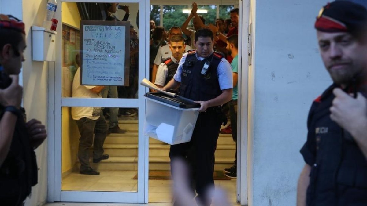 Un mosso se lleva una urna de un colegio durante el referéndum del 1-O-. / RICARD CUGAT
