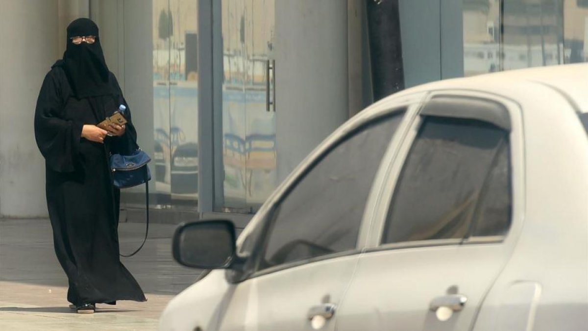 Una mujer saudí camina junto a un coche en una calle de Riad, la capital de Arabia Saudí, el 27 de septiembre.-AFP / FAYEZ NURELDINE