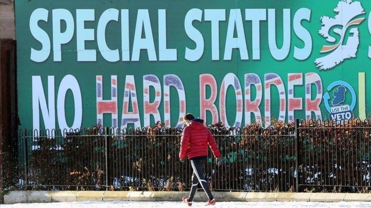 Un peatón pasa junto a un cartel en Belfast sobre el Sinn Féin rechazando una frontera dura.-AFP (PAUL FAITH)