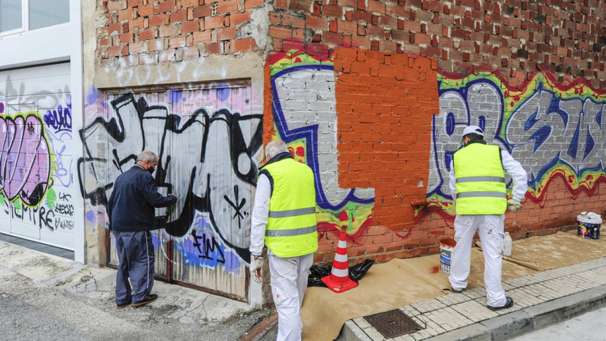 Trabajadores de los planes de empleo, de anteriores ejercicios, limpiando una pintada vandálica.