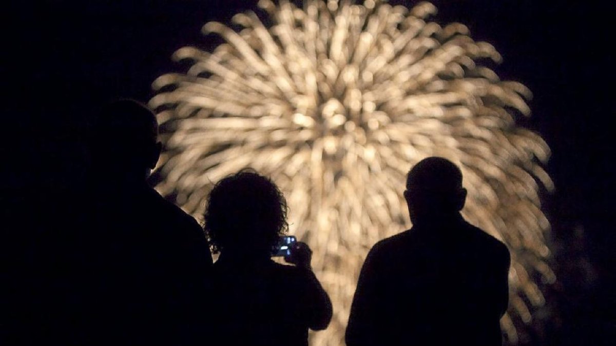 Varias personas contemplan los fuegos artificiales.-P. REQUEJO