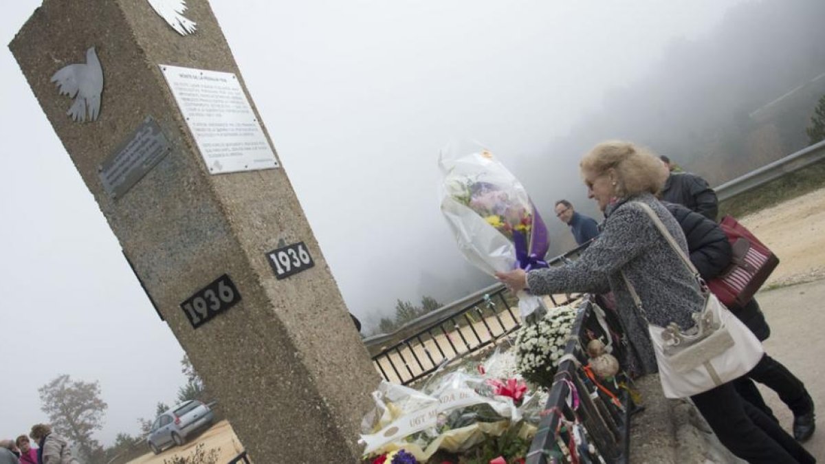 Una mujer deposita flores junto al monolito en recuerdo de los fusilados durante la Guerra Civil.-ICAL