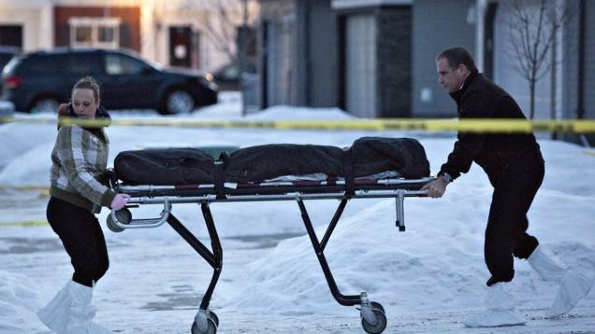 Dos agentes se llevan uno de los cadáveres encontrados en una casa de Edmonton, este martes.-Foto: AP / JASON FRANSON