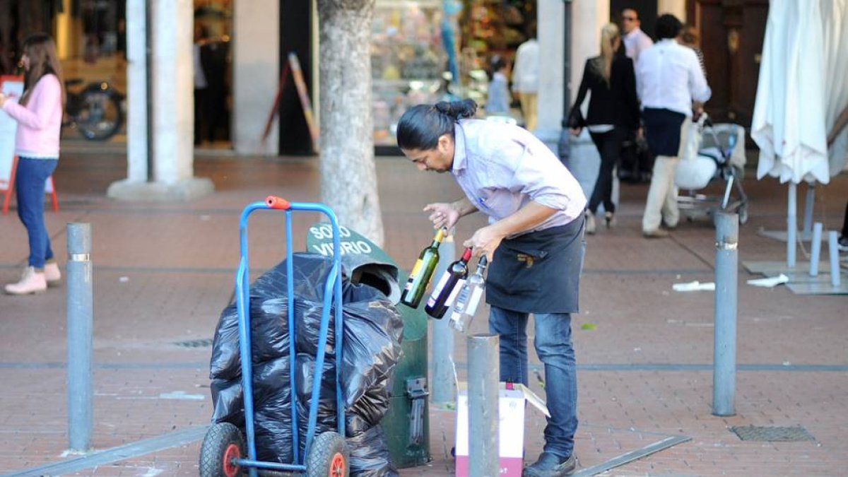 Un hombre recicla envases de vidrio en un contenedor verde instalado en la Plaza Mayor.