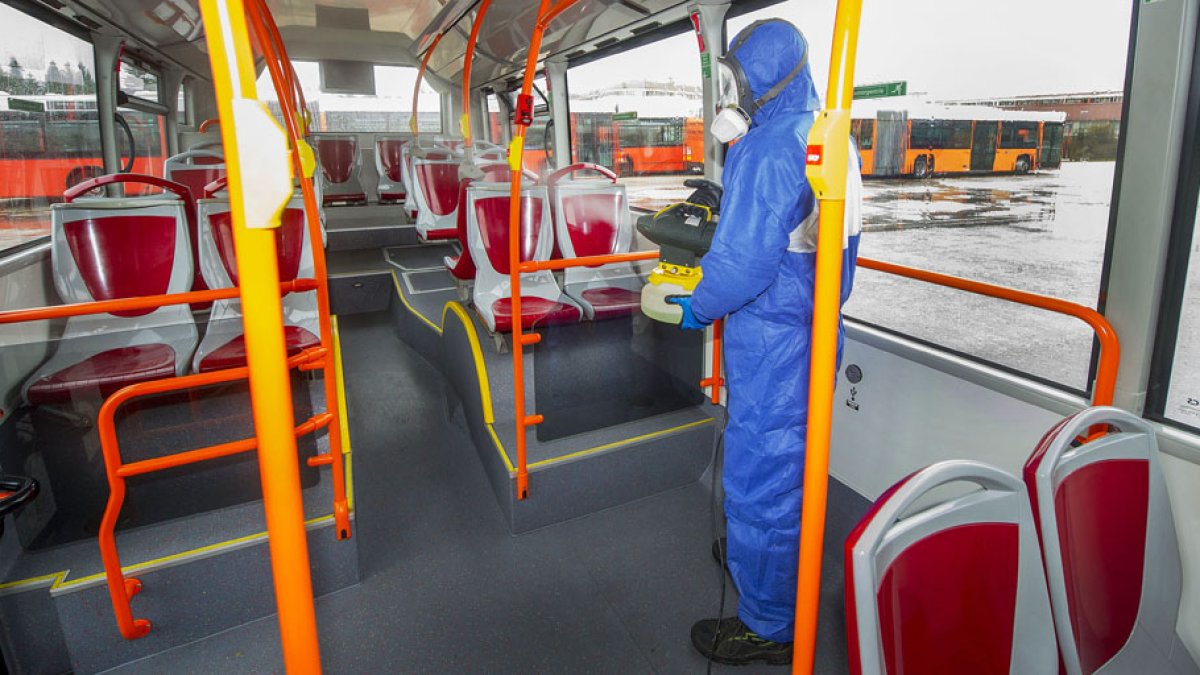 Un operario desinfecta uno de los autobuses urbanos en las cocheras de la carretera Poza. ISRAEL L. MURILLO