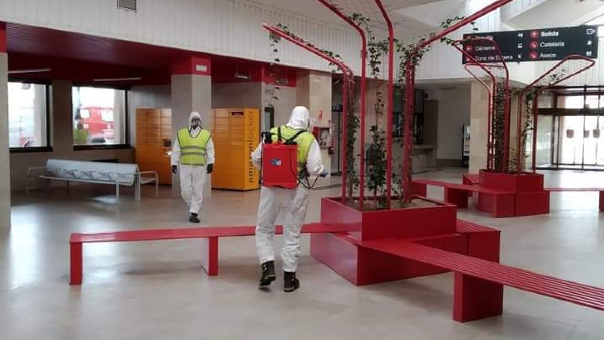 Dos bomberos desinfectan el interor de la estación de trenes. ECB