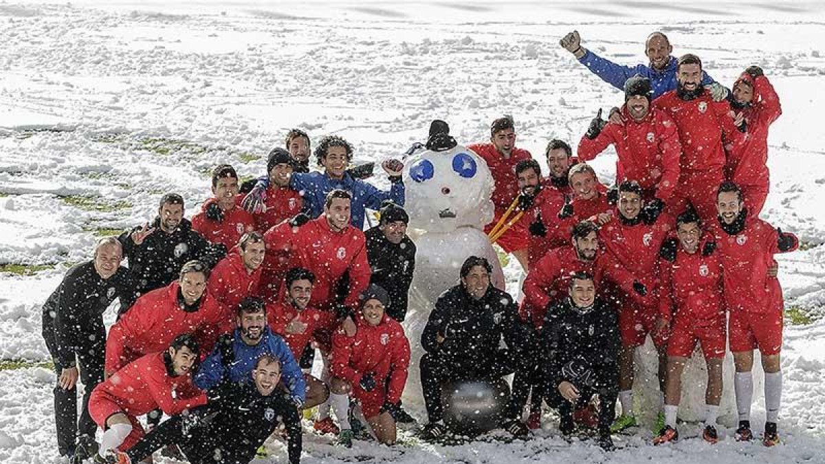 Jugadores y cuerpo técnico del Burgos CF posan con el muñeco de nieve levantado sobre el césped de El Plantío, ayer.-SANTI OTERO