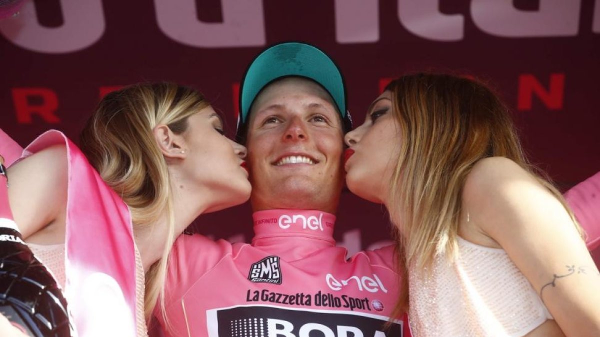 Lukas Pöstlelberger recibe los besos de las azafatas, en un podio a la vieja usanza.-AFP