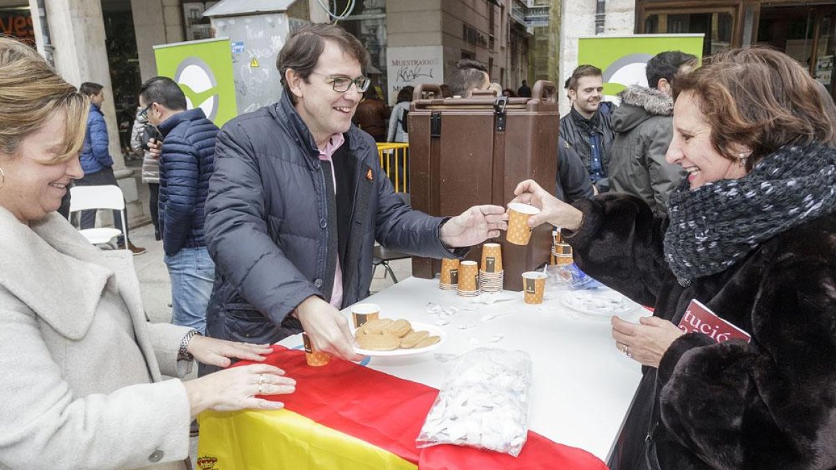 Alfonso Fernández Mañueco entrega un chocolate y unos bizcochos a una mujer, ayer, en la Plaza Mayor.-SANTI OTERO