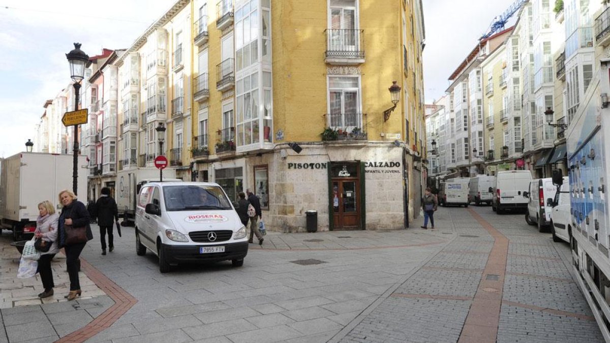Furgonetas y camiones de reparto estacionados y circulando en las calles Laín Calvo y Avellanos.