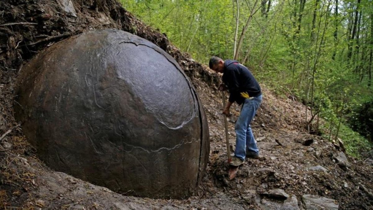Suad Keserovic limpia la esfera de piedra en Podubravije, cerca de Zavidovici (Bosnia), el 11 de abril.-REUTERS / DADO RUVIC