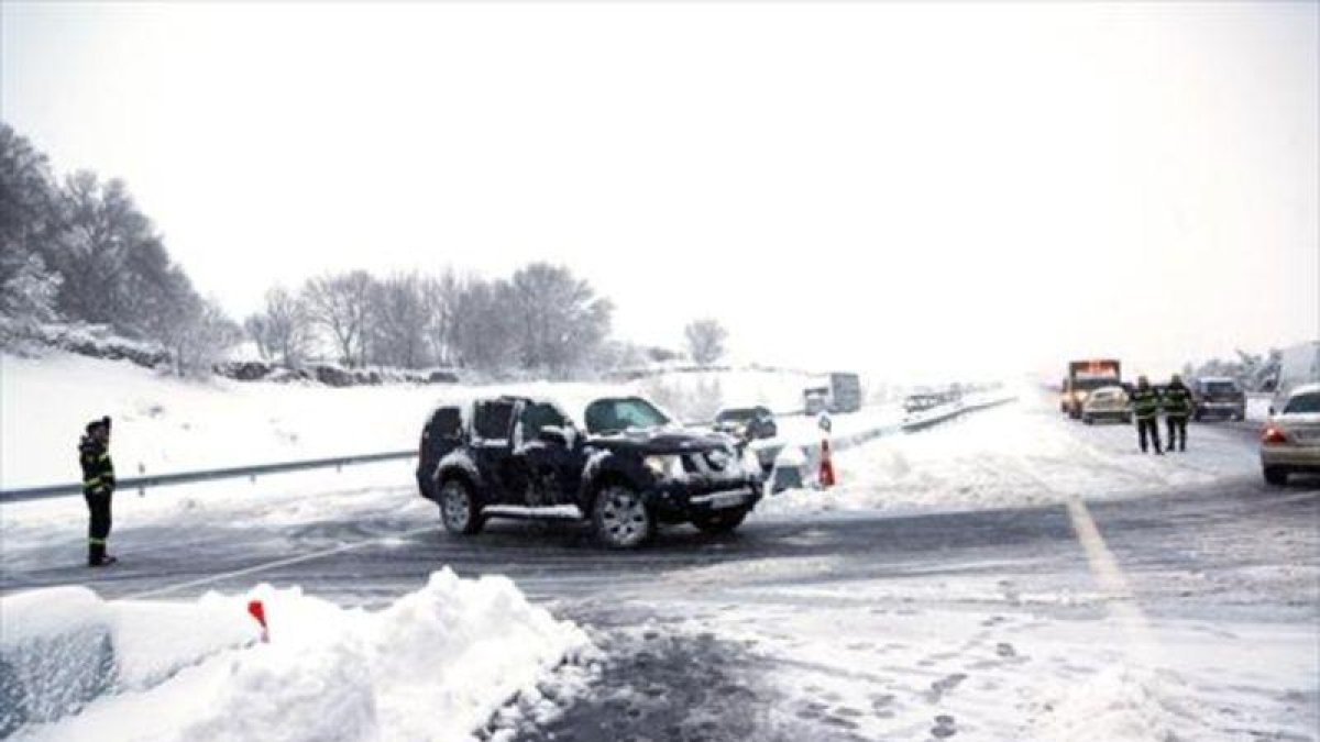 Agentes de la policía ayudan el domingo a los vehículos atrapados en la AP-6 por la tormenta de nieve.-EFE / LUISMI ORTIZ