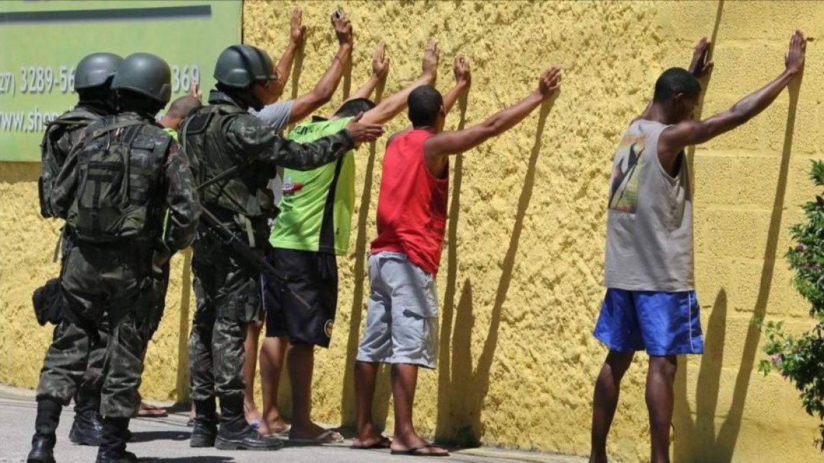 Policías militares cachean a sospechosos en Vila Velha, en el estado de Espirito Santo.-PAULO WHITAKER / REUTERS