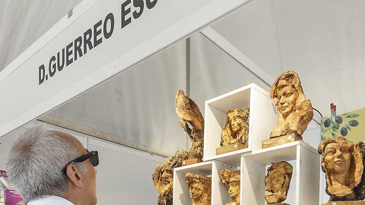 Un hombre observa varias piezas de madera en la feria.-SANTI OTERO