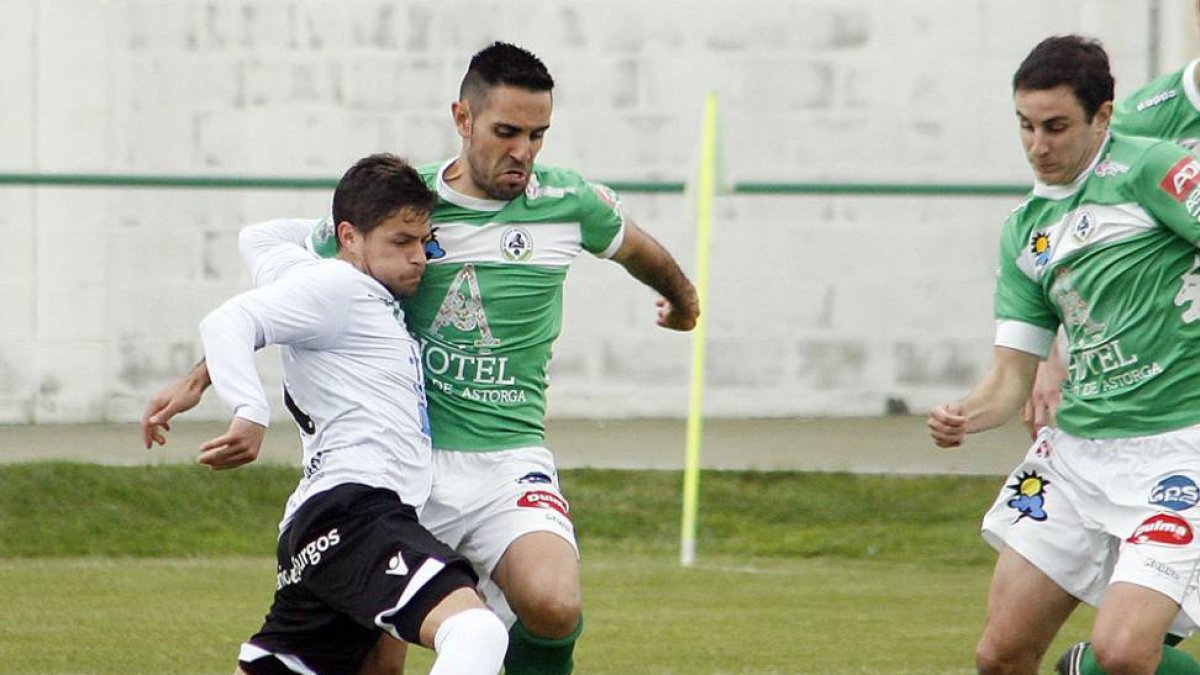 Álex Cruz trata de marcharse entre dos jugadores del Atlético Astorga.-BRUNO MORENO