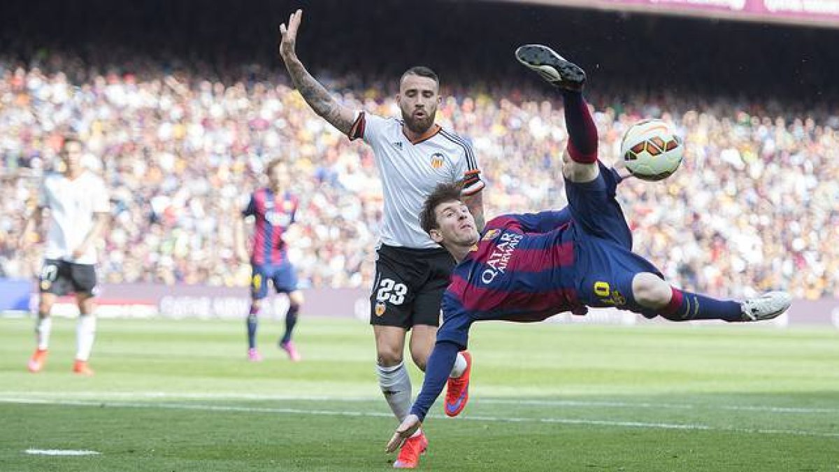 Messi chuta acrobáticamente ante Otamendi, durante el Barcelona-Valencia en el Camp Nou.-Foto: JORDI COTRINA