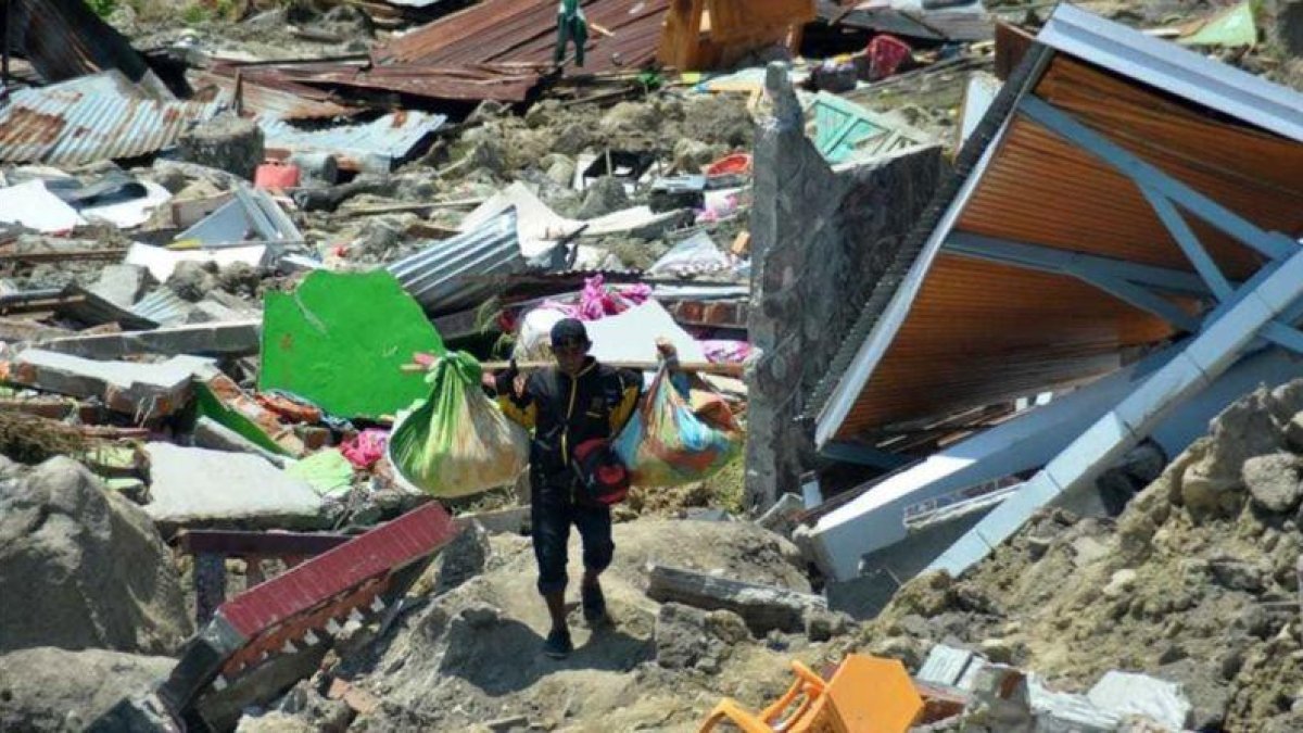 Un hombre carga objetos personales entre los escombros de un edificio derrumbado por el terremoto, en la ciudad indonesia de Palu.-RIFKI (AP)
