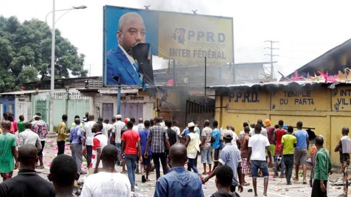Opositores del presidente Kabila gritan consignas contra el mandatario mientras destruyen un cartel con su imagen, en Kinshasa, capital de la República Democrática del Congo, este lunes.-REUTERS / KENNY KATOMBE