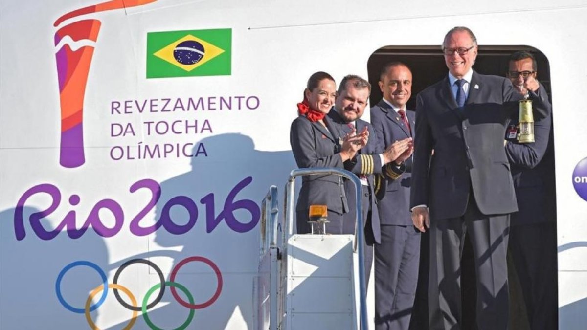 El presidente del Comite Olímpico Brasileño, Carlos Arthur Nuzman, transporta la linterna con el fuego olímpico a su llegada a Brasilia.-AFP / EVARISTO SA