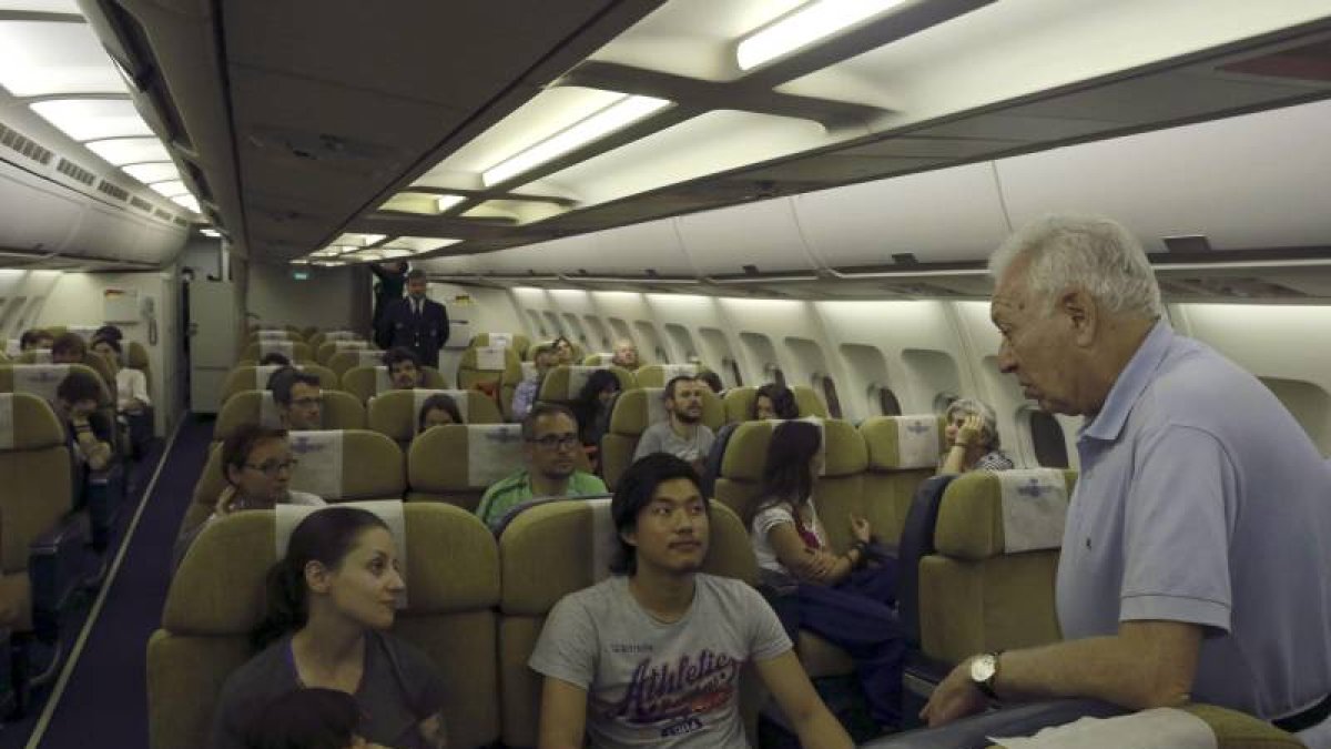 El ministro de Asuntos Exteriores, José Manuel García-Margallo (d), conversa con varios de los españoles rescatados tras el terremoto de Nepal en el avión que les ha traído a España desde Nueva Delhi.-Foto: EFE
