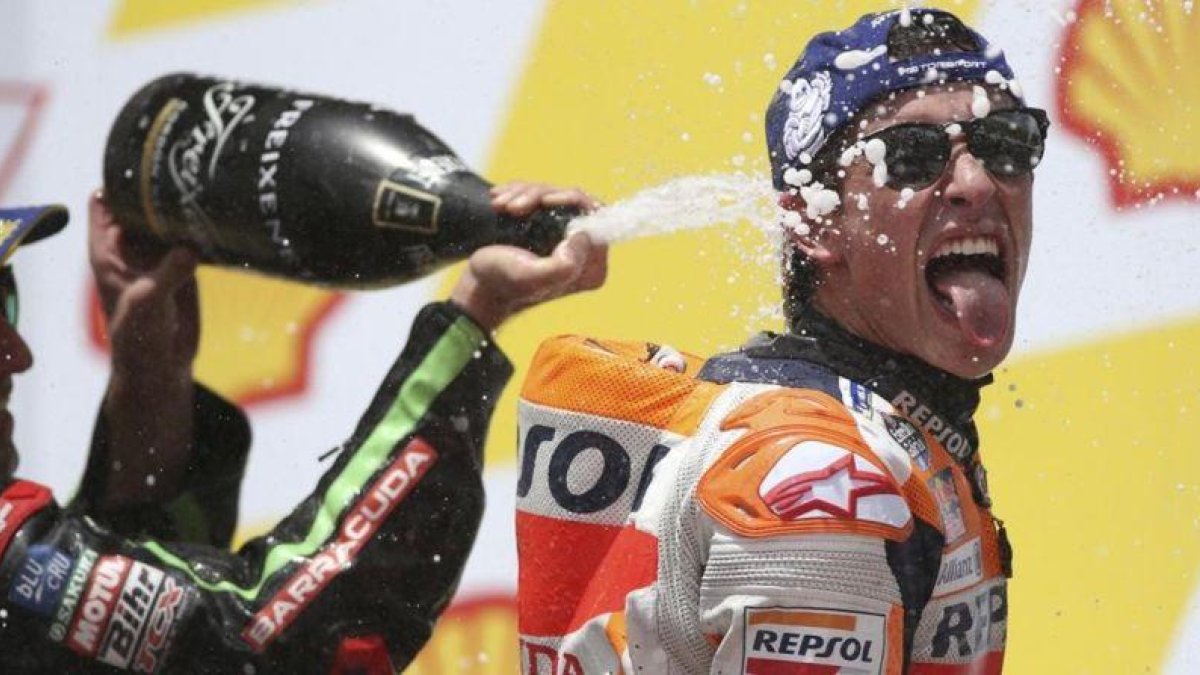 Johann Zarco (Yamaha) ducha a Marc Márquez (Honda), en el podio de Sepang (Malasia).-AP / VICENT PHOON