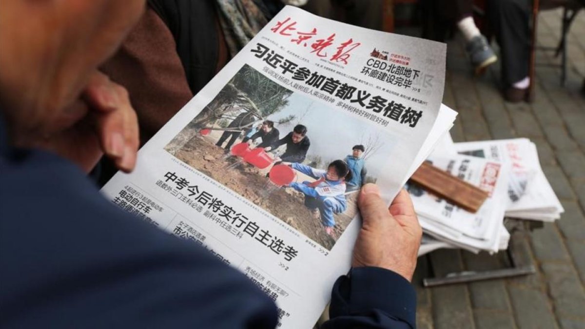 Un hombre lee un periódico donde aparece en portada el presidente Xi en una plantación de árboles, el 6 de abril, en Pekín.-AFP