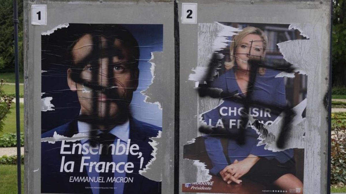 Pintadas en carteles electorales de Macron y Le Pen.-AFP / DAMIEN MEYER