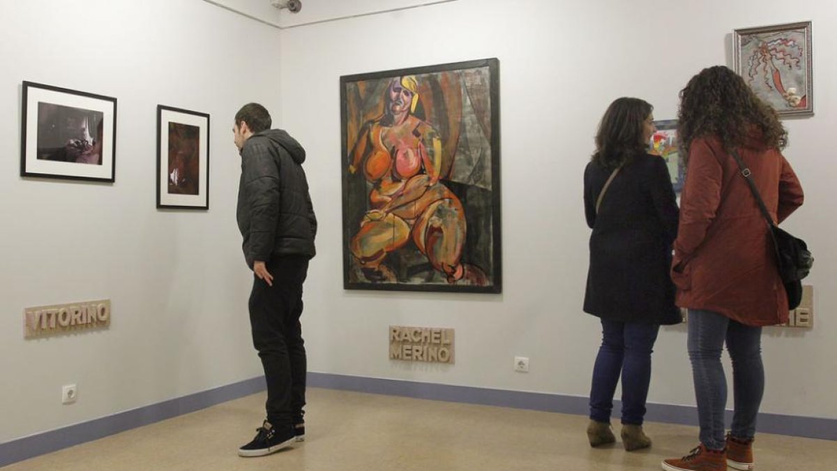 Un chico mira las fotos de Vitorino y unas chicas, los dibujos de Cinta Aller, con la pintura de Rachel Merino en medio.-Santi Otero