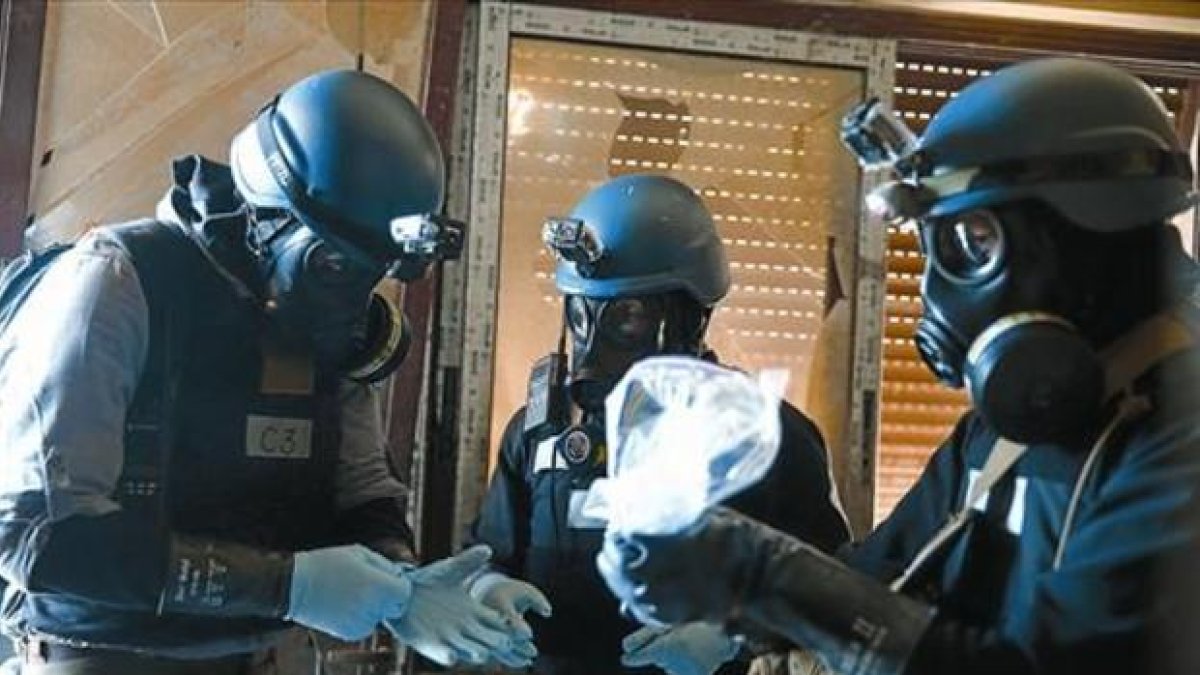 Supervisión - Unos inspectores examinan material en una zona atacada con armas químicas en Siria. /-REUTERS