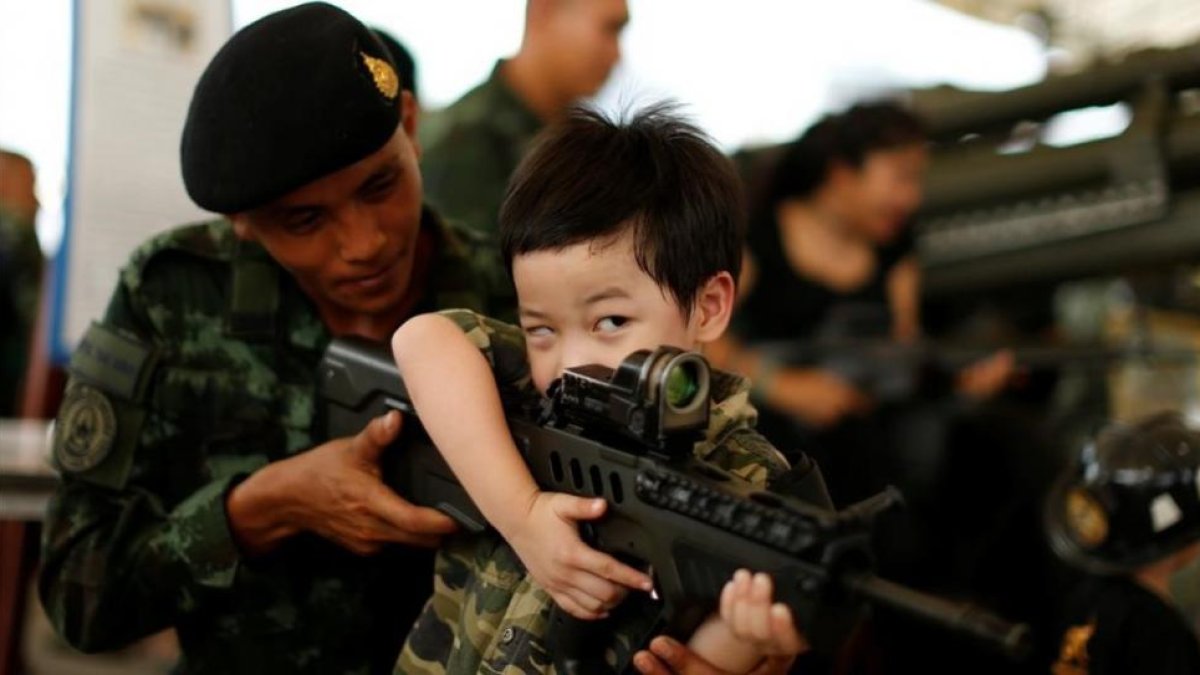 Un soldado tailandés muestra a un niño cómo funciona un arma en la celebración del Día del Niño.-REUTERS / JORGE SILVA